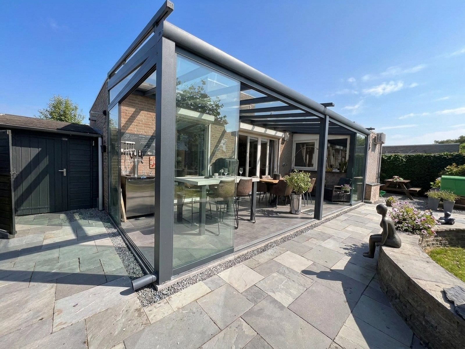 Aluminium veranda met glazen schuifwanden aan een woning in de avond